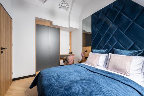 a bedroom with a blue bed with a large headboard at Wrota Chałubińskiego in Zakopane