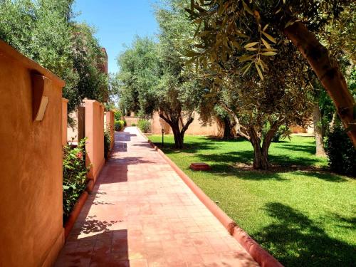a brick path in a garden with trees and grass at La Maison Des Oliviers in Marrakesh