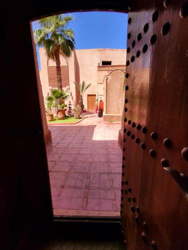 an open door to a courtyard with a palm tree at La Maison Des Oliviers in Marrakesh