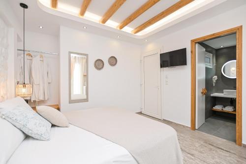 a white bedroom with a bed and a tv at Blue Sky Summer in Naxos Chora