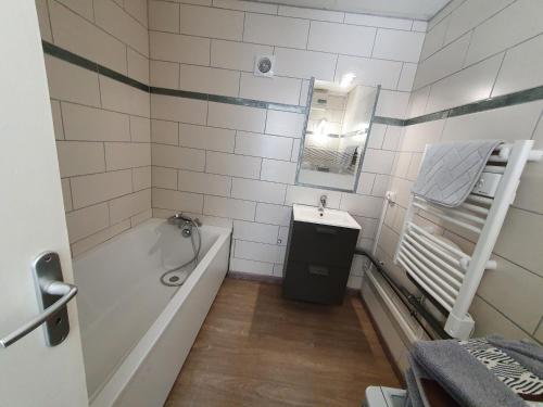 y baño con bañera y lavamanos. en Appartement spacieux en Salins-les-Bains