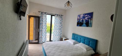 a bedroom with a bed with a blue headboard and windows at Stablo guest house in Bărăşti