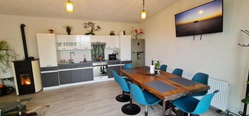 a kitchen with a wooden table and blue chairs at Stablo guest house in Bărăşti