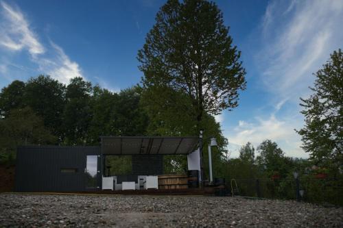 a small black building with a tree in the background at Stablo guest house in Bărăşti