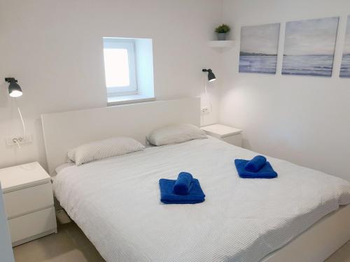 Apartment House Bucul في مالي لوسيني: سرير أبيض وفوط زرقاء فوقه
