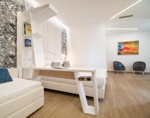 einen weißen Schreibtisch in einem weißen Zimmer mit einem Sofa in der Unterkunft One Design Hotel in Rimini