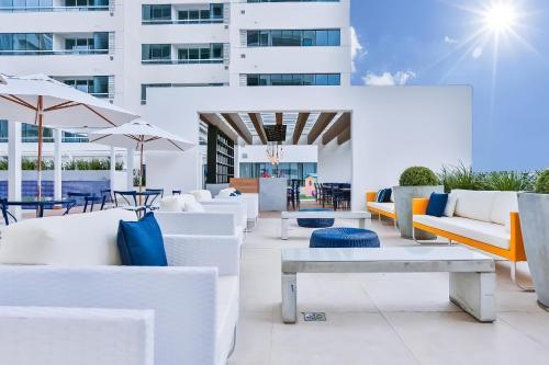 a patio with white furniture and tables and umbrellas at True América apart-hotel in Campos dos Goytacazes
