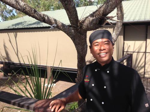 a man in a black uniform standing next to a tree at Bamurru Plains in Point Stuart