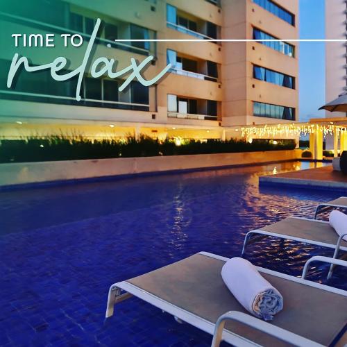 a pool with two lounge chairs next to a building at América apart-hotel in Campos dos Goytacazes