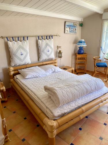 - une chambre avec un grand lit et un cadre en bois dans l'établissement Chambre d'hôtes La Belgerie, à Saint-Michel-en-lʼHerm