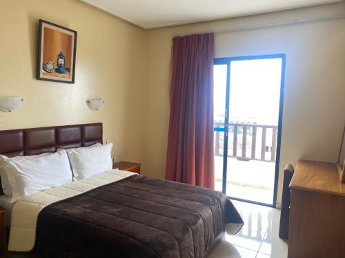 Habitación de hotel con cama y puerta corredera de cristal en Hotel Residence Rihab, en Agadir