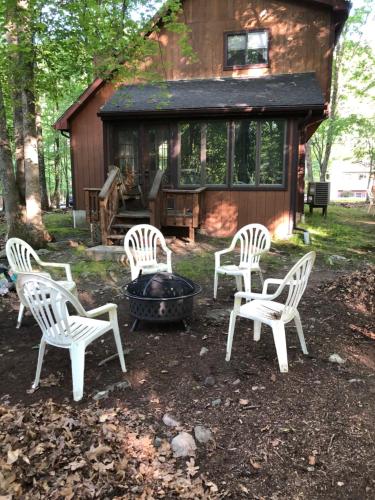four white chairs and a fire pit in front of a cabin at My Little Flagship Cabin in East Stroudsburg