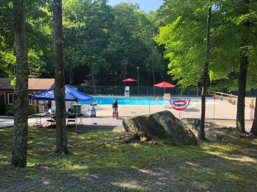 a park with a swimming pool with people and umbrellas at My Little Flagship Cabin in East Stroudsburg