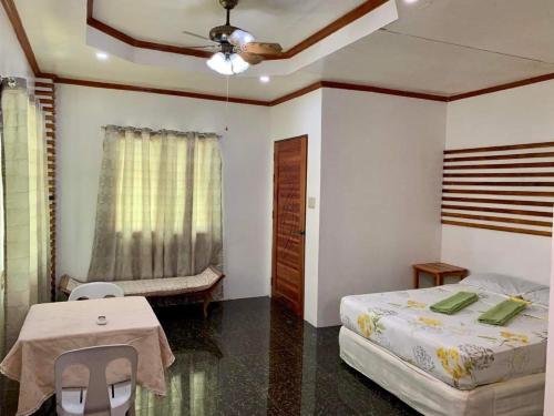 a bedroom with a bed and a table and a ceiling at Pore's Homestay in General Luna