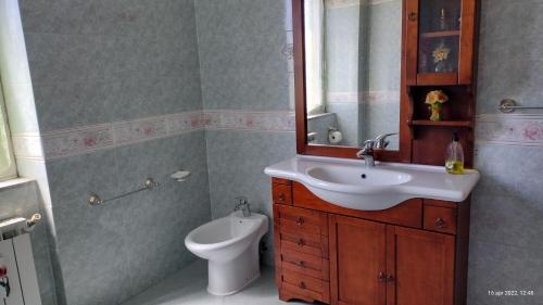 een badkamer met een wastafel, een toilet en een spiegel bij Villa Grazia in Ladispoli