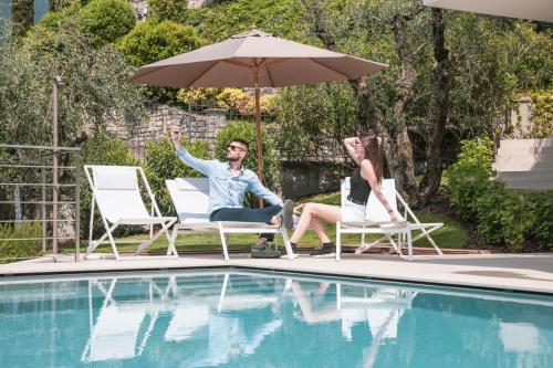 a man and woman sitting under an umbrella next to a pool at Verdolivo in Sale Marasino