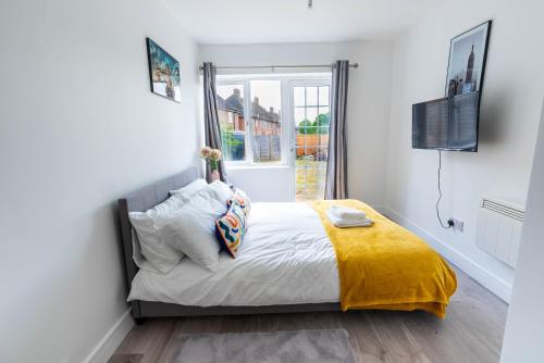 a bedroom with a bed with a yellow blanket and a window at Flat 04 Studio flat close to Aylesbury town and Station Free Parking in Buckinghamshire