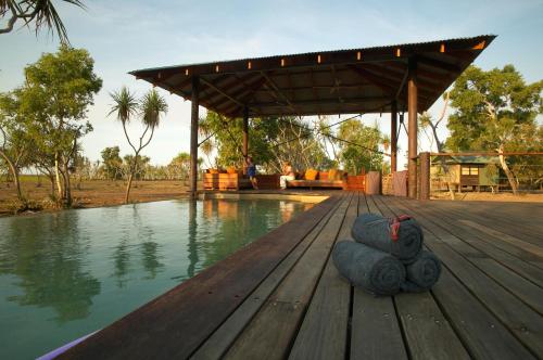 a wooden deck with a pool of water and a pavilion at Bamurru Plains in Point Stuart