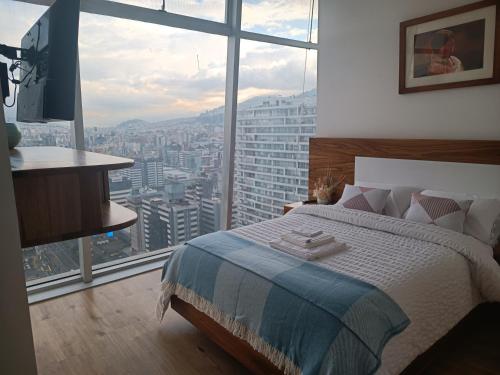 a bedroom with a bed and a large window at Hermoso Penthouse Vistas Espectacular in Quito