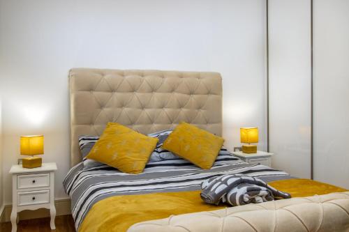 a bedroom with a bed with yellow pillows and two lamps at 602 Luxury Apartment near Luton Town and Station in Luton