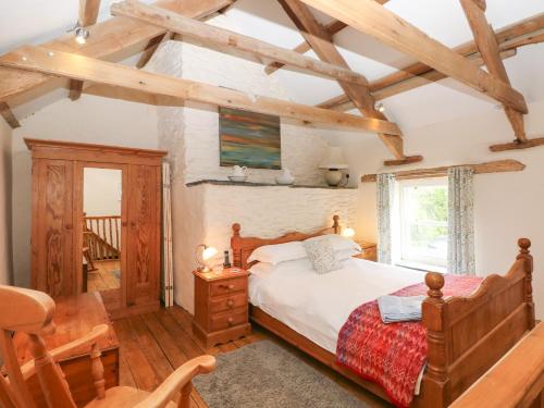 a bedroom with a bed in a room with wooden beams at Bwthyn Y Felin Star in Clydey