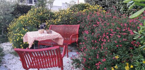 two red chairs and a table in a garden with flowers at Appartement à 8 km de la mer - 3 chambres in Vendres