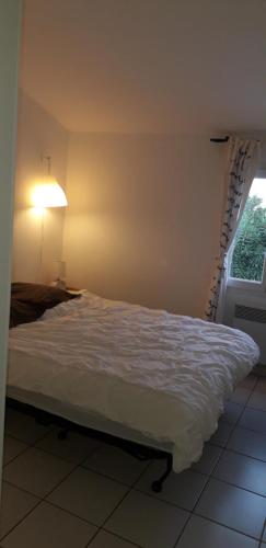 uma cama num quarto com um candeeiro e uma janela em Appartement à 8 km de la mer - 3 chambres em Vendres
