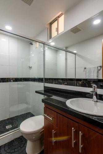 a bathroom with a toilet and a sink and a mirror at Hotel Med Estadio in Medellín
