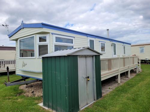 a green and white house with a green shed at 8 Berth on Sealands Everglade III in Ingoldmells