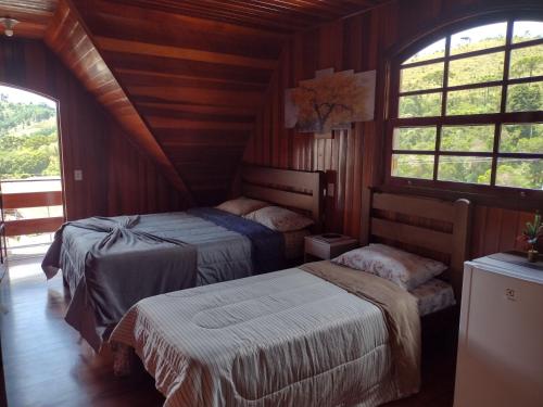 a bedroom with two beds in a room with windows at Casa do Trem Suítes in Campos do Jordão