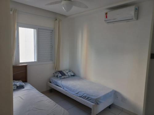 a small bedroom with two beds and a window at Apartamento 500m Praia da Enseada Guarujá varanda e vaga de garagem in Guarujá