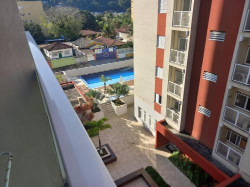 a view from the balcony of a building with a swimming pool at Apartamento 500m Praia da Enseada Guarujá varanda e vaga de garagem in Guarujá
