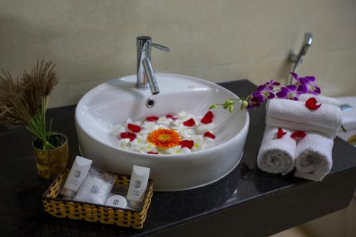 a bathroom sink with flowers and towels on a counter at Han Huyen Homestay in Hoi An