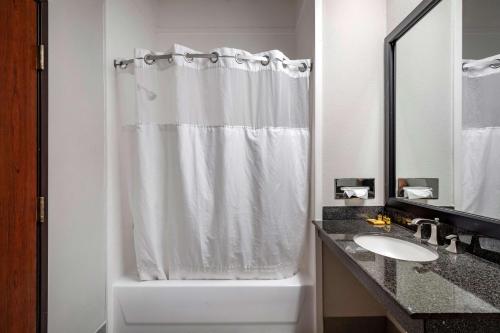 a bathroom with a white shower curtain and a sink at Best Western Plus McKinney Inn and Suites in McKinney