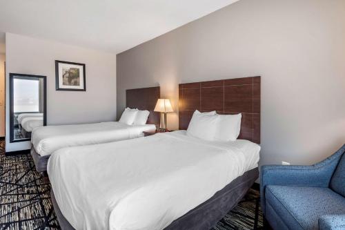 a hotel room with two beds and a blue chair at Best Western Plus McKinney Inn and Suites in McKinney