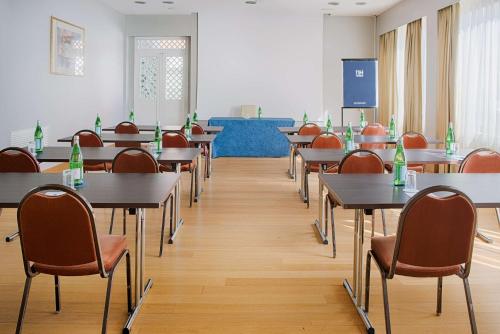 a classroom with tables and chairs and a screen at NH Ravenna in Ravenna