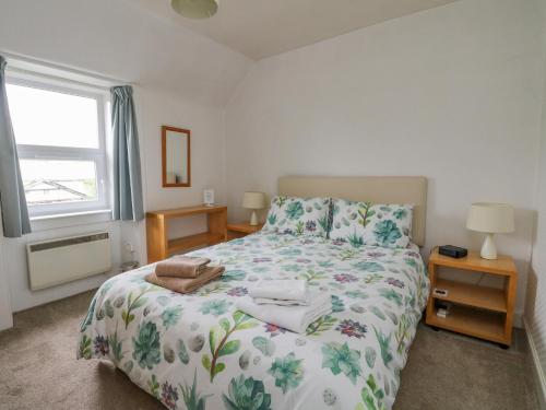 1 dormitorio con 1 cama con colcha de flores en The Knowe Upper, en Taynuilt