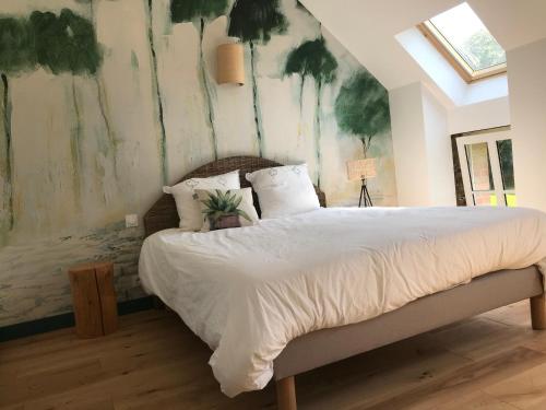 a bedroom with a large bed with a painting on the wall at Escale de Gerbold in Gratot
