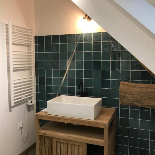 a bathroom with a sink and a green tiled wall at Escale de Gerbold in Gratot