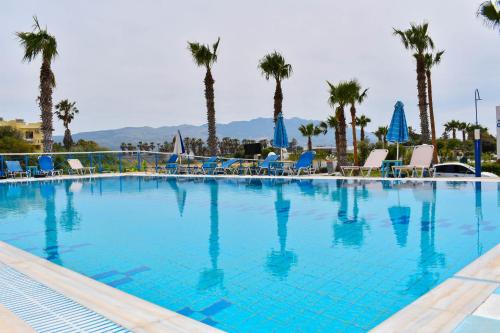 a large swimming pool with chairs and palm trees at LambiSea Apartment 2 in Kos