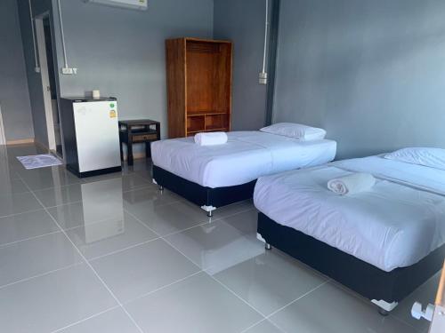 a room with two beds and a tv in it at บ้านพิชชา ที่พักใจกลางเมืองปราณบุรี in Ban Khao Noi