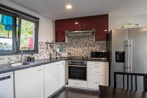 a kitchen with white cabinets and a stainless steel refrigerator at Alojamento de Crasto - Gerês in Geres