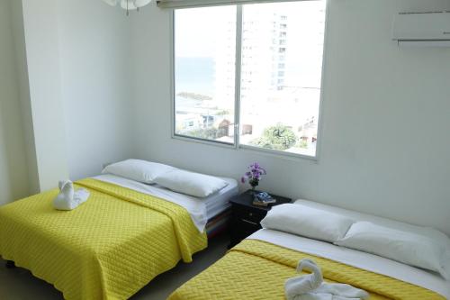 a room with two beds with yellow sheets and a window at Edificio Galatea in Manta