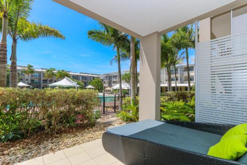 un patio con banco, palmeras y piscina en Peppers Salt Resort & Spa - Lagoon pool access 2 br spa suite, en Kingscliff