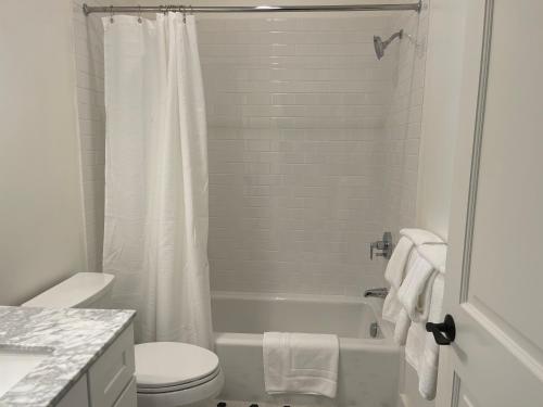 a white bathroom with a toilet and a bath tub at The Gables Inn Sausalito in Sausalito