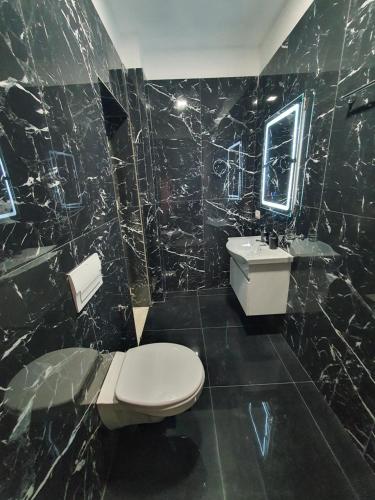a black tiled bathroom with a toilet and a sink at Villa Mehmeti in Sarandë