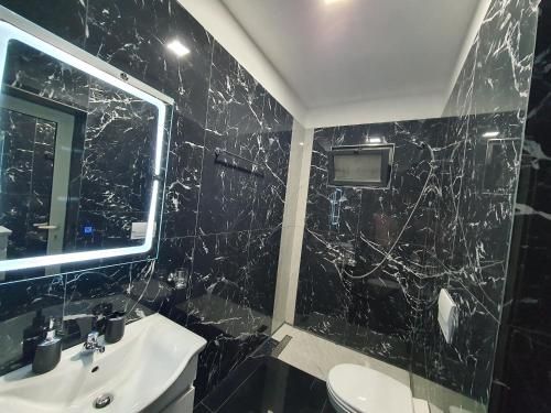 a black bathroom with a sink and a mirror at Villa Mehmeti in Sarandë
