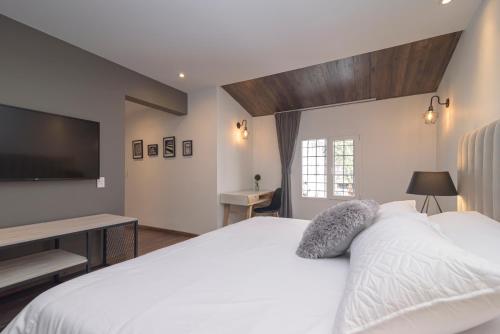 a bedroom with a white bed and a flat screen tv at Casa Lorenzo Bogota in Bogotá