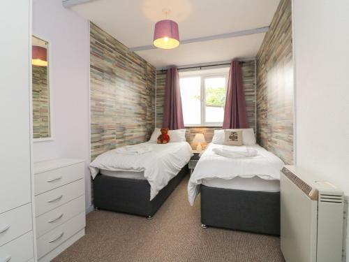 two twin beds in a bedroom with a window at The Stables in Holsworthy