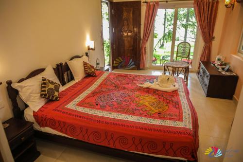a bedroom with a large bed with a red bedspread at Vishram Village in Varkala